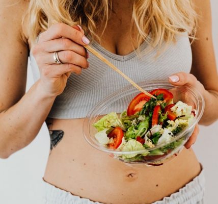 Woman in sports attire enjoys a fresh, nutritious salad, embodying a healthy lifestyle.